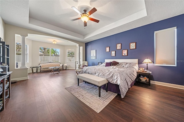 bedroom featuring dark hardwood / wood-style flooring, a textured ceiling, a raised ceiling, and ceiling fan