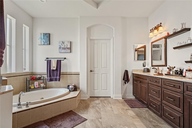 bathroom featuring vanity and tiled bath