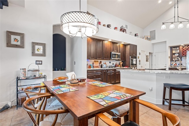 dining space with sink, high vaulted ceiling, light tile patterned floors, and an inviting chandelier