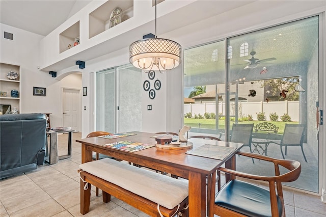 tiled dining space with ceiling fan with notable chandelier and built in features