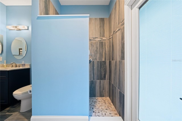 bathroom with vanity, tiled shower, toilet, and tile patterned flooring