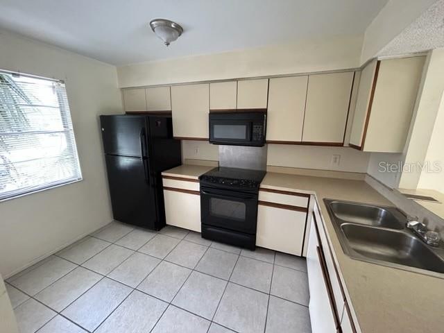 kitchen featuring black appliances, sink, and light tile patterned floors