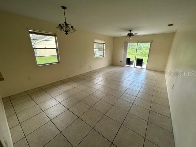 354 Camillia Ln Unit B, Port Charlotte, FL 33954 - empty room featuring light tile patterned floors, a chandelier, and ceiling fan