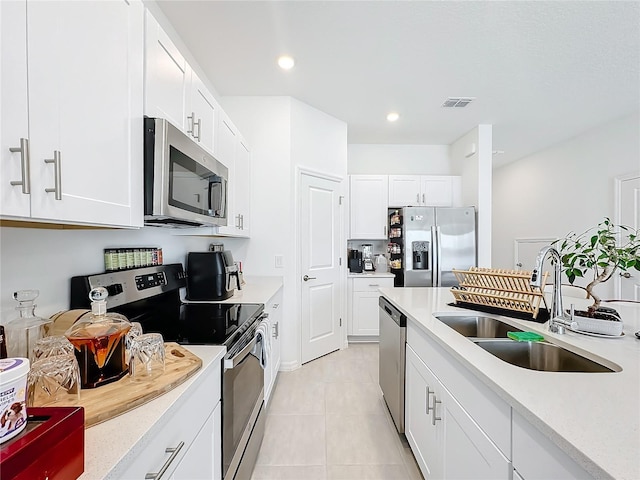 kitchen featuring appliances with stainless steel finishes, light tile patterned flooring, white cabinets, and sink