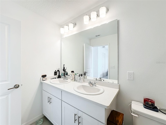 bathroom with vanity, toilet, and a textured ceiling