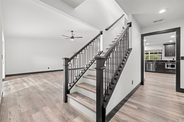 stairs with hardwood / wood-style floors and ceiling fan