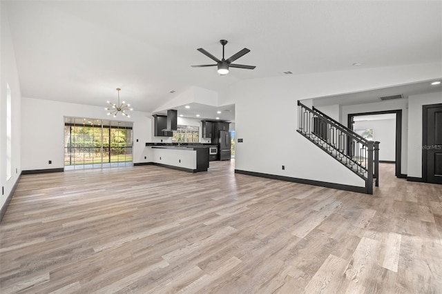 unfurnished living room with lofted ceiling, ceiling fan with notable chandelier, and light wood-type flooring