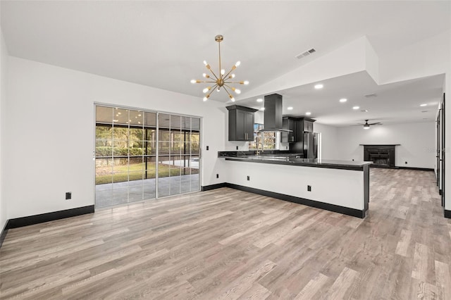 kitchen with island range hood, kitchen peninsula, light hardwood / wood-style floors, and stainless steel refrigerator