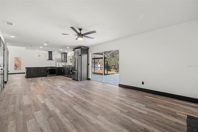 unfurnished living room with hardwood / wood-style flooring and ceiling fan with notable chandelier