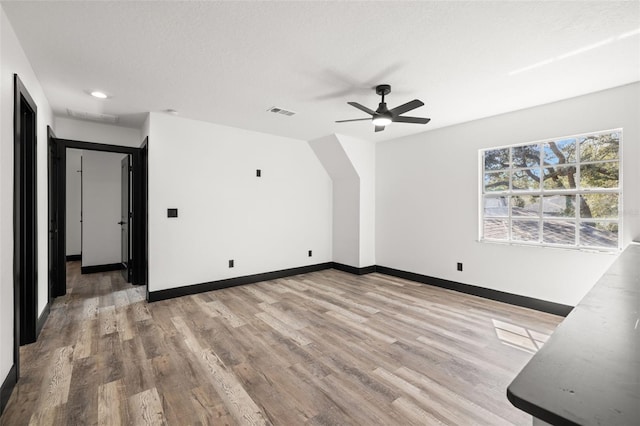 unfurnished living room with a textured ceiling, light wood-type flooring, and ceiling fan