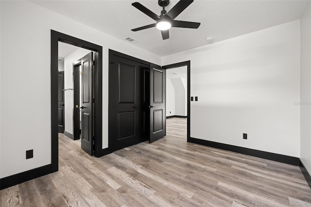 unfurnished bedroom featuring light hardwood / wood-style flooring, a textured ceiling, and ceiling fan