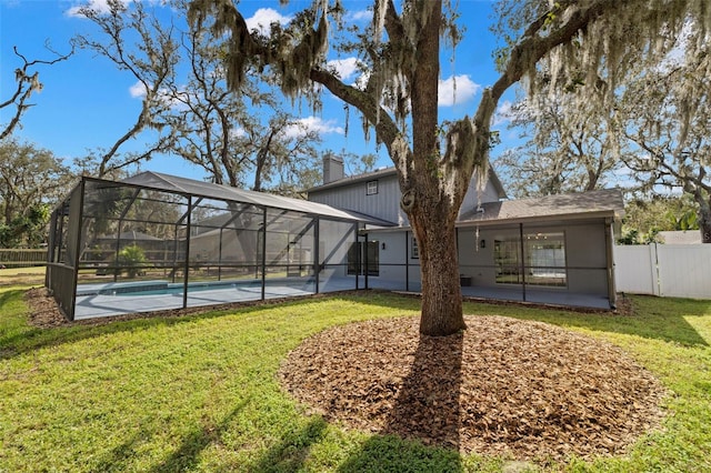 back of house featuring a lawn, a fenced in pool, a patio, and glass enclosure