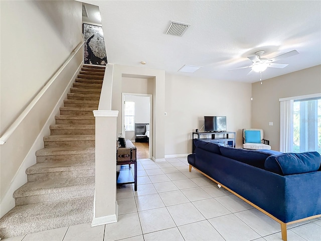 living room featuring ceiling fan, a textured ceiling, and light tile patterned floors