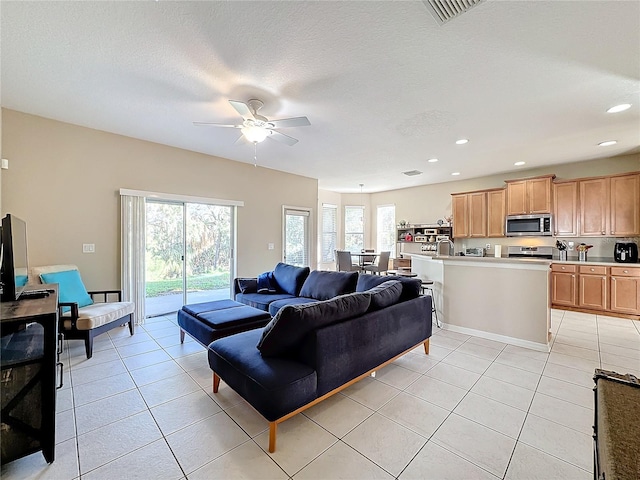 tiled living room featuring a textured ceiling, sink, and ceiling fan