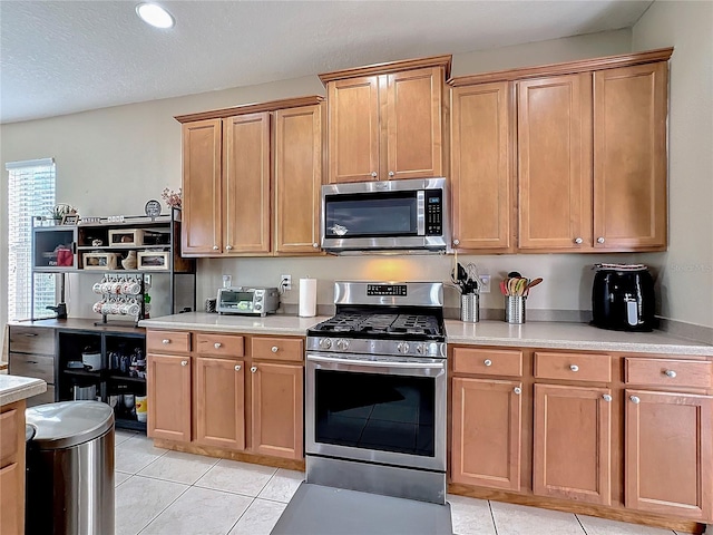 kitchen featuring appliances with stainless steel finishes, a textured ceiling, and light tile patterned floors