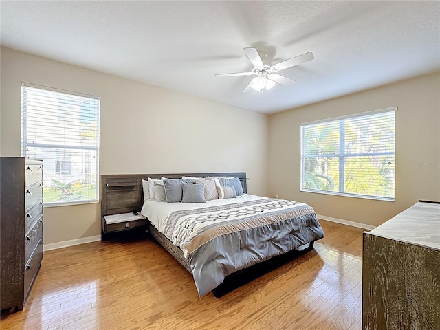 bedroom featuring light hardwood / wood-style flooring, multiple windows, and ceiling fan