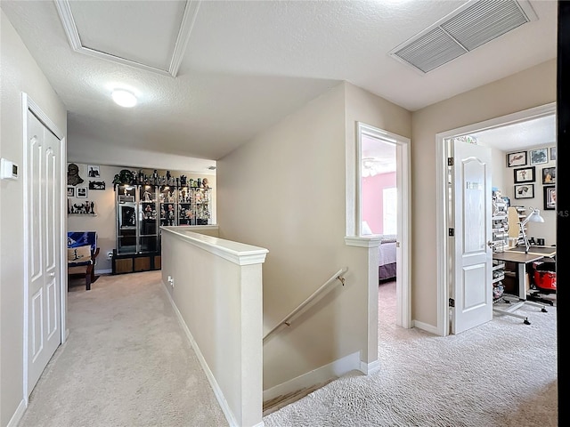 hall featuring a textured ceiling and light colored carpet