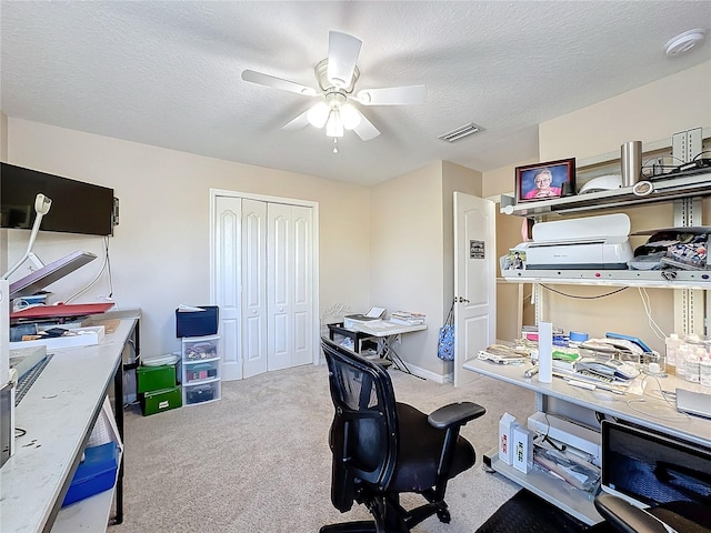 office space with light carpet, a textured ceiling, and ceiling fan