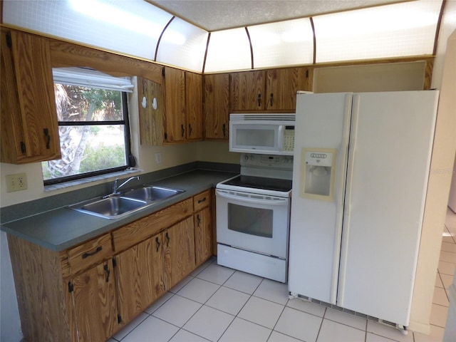 27242 Sunnybrook Rd Unit B, Punta Gorda, FL 33983 - kitchen with white appliances, a sink, dark countertops, light tile patterned flooring, and brown cabinets