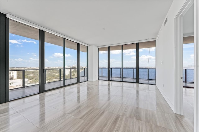 unfurnished room featuring expansive windows, a wealth of natural light, and a water view