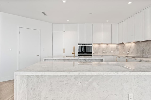 2912 W Santiago St Unit 1901, Tampa, FL 33629 - kitchen with light wood-type flooring, tasteful backsplash, white cabinets, and recessed lighting