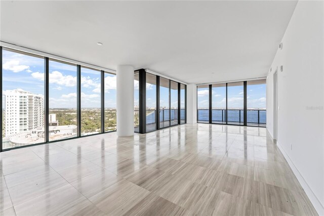 empty room with a wealth of natural light, expansive windows, and a water view