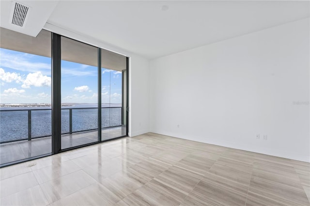 tiled empty room featuring a wall of windows and a water view