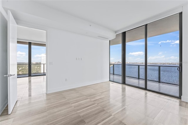 spare room featuring a wall of windows and a water view