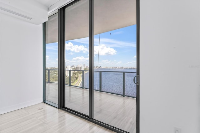 unfurnished room with a wall of windows and a water view