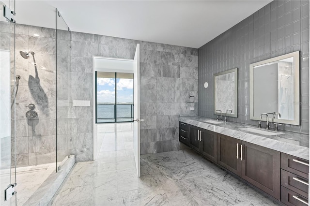 bathroom featuring tile walls, walk in shower, a water view, and vanity