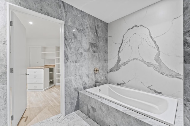 bathroom featuring tile walls and a relaxing tiled tub