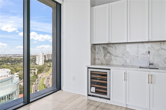 bar with white cabinets, beverage cooler, and sink