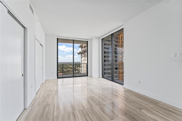 unfurnished room with expansive windows and light hardwood / wood-style floors