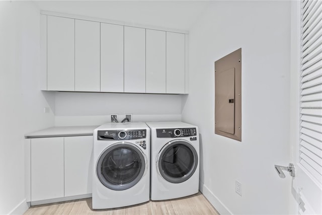 clothes washing area with electric panel, light hardwood / wood-style floors, cabinets, and independent washer and dryer