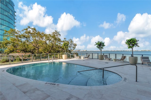 view of swimming pool with a water view and a patio