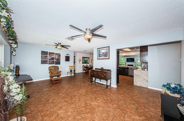 living room featuring ceiling fan and a textured ceiling