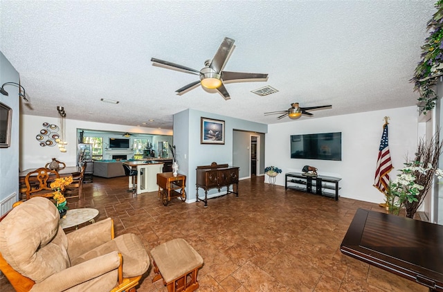 living room with ceiling fan and a textured ceiling