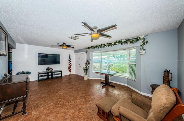 living area with a textured ceiling and ceiling fan