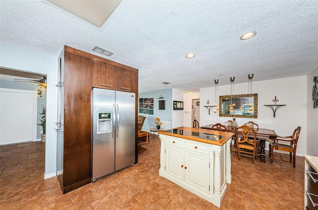 13191 92nd Ave, Seminole, FL 33776 - kitchen featuring stainless steel fridge with ice dispenser, a textured ceiling, wooden counters, white cabinets, and a center island