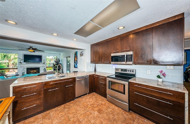 kitchen featuring stainless steel appliances, a textured ceiling, and light stone counters