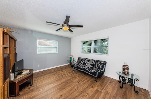 living area with hardwood / wood-style floors, ceiling fan, and a textured ceiling