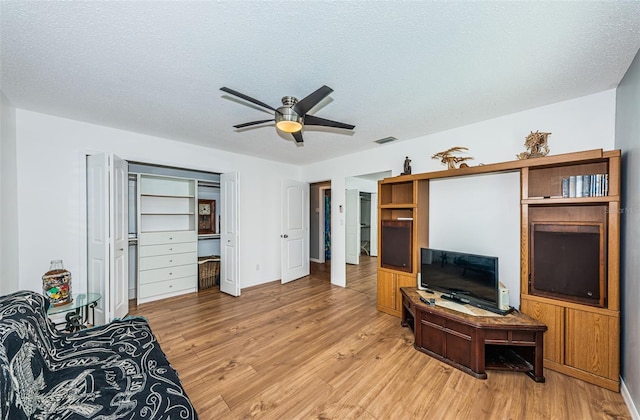 living room featuring a textured ceiling, light hardwood / wood-style floors, and ceiling fan