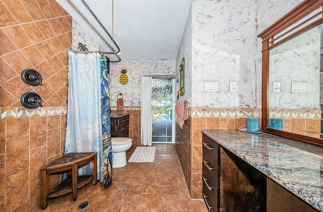13191 92nd Ave, Seminole, FL 33776 - full bathroom featuring a tile shower, toilet, a textured ceiling, vanity, and tile walls