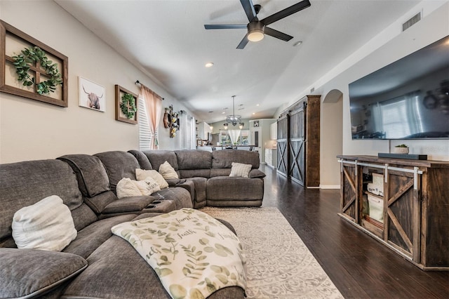 living room featuring ceiling fan with notable chandelier, dark hardwood / wood-style flooring, and a barn door