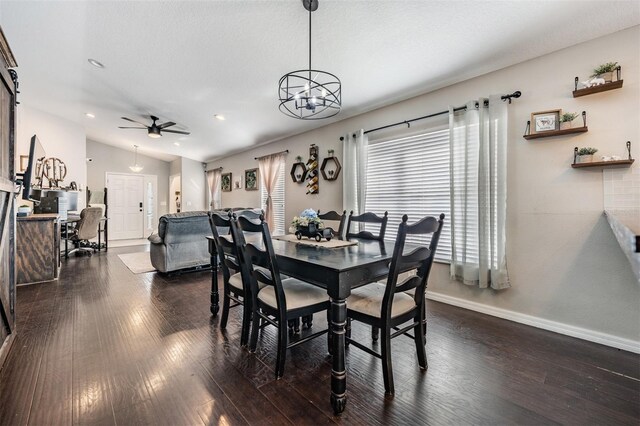 dining room with lofted ceiling, a barn door, dark hardwood / wood-style floors, and ceiling fan with notable chandelier