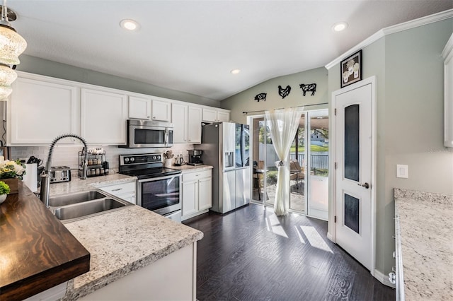 kitchen with tasteful backsplash, hanging light fixtures, appliances with stainless steel finishes, white cabinetry, and sink