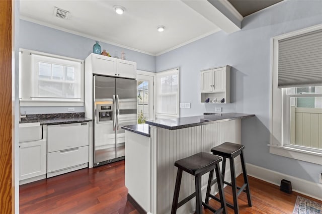 kitchen featuring stainless steel fridge, white cabinets, kitchen peninsula, and plenty of natural light