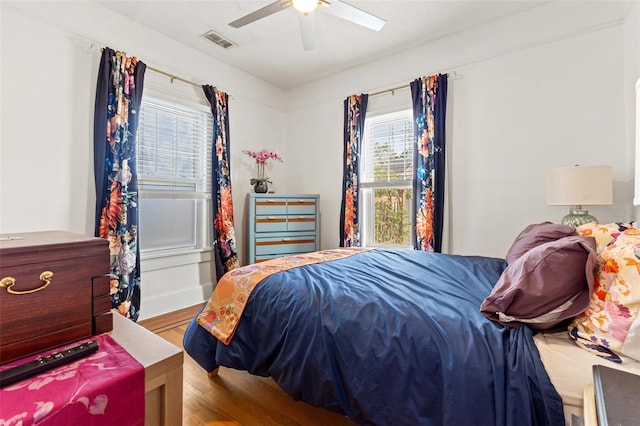 bedroom featuring ceiling fan, wood-type flooring, and multiple windows