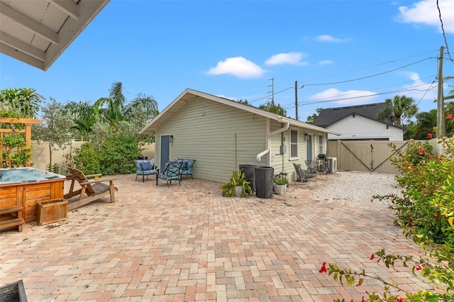 exterior space with a hot tub, central air condition unit, and a patio