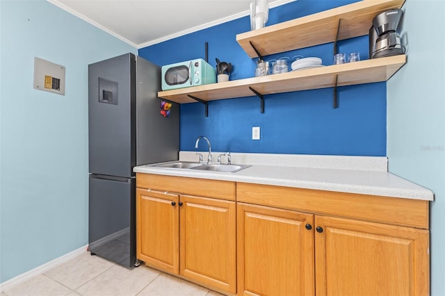 kitchen featuring sink, light tile patterned flooring, crown molding, and black fridge